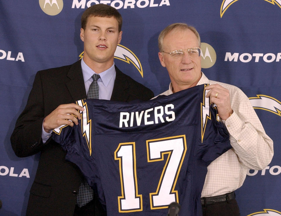 FILE - In this April 25, 2004, file photo, San Diego Chargers quarterback Philip Rivers, left, holds up his Chargers jersey with coach Marty Schottenheimer at a news conference in San Diego. The Chargers traded No. 1 draft pick Eli Manning to the New York Giants for Rivers and future draft picks. On Wednesday, Jan. 20, 2021, 39-year-old Indianapolis Colts quarterback Philip Rivers announced his retirement. (AP Photo/Denis Poroy, FIle)