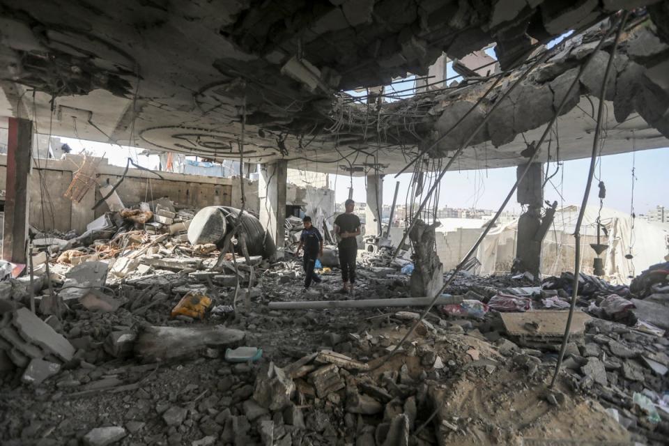 Palestinians stand in the ruins of a family home after an overnight Israeli attack (AP)