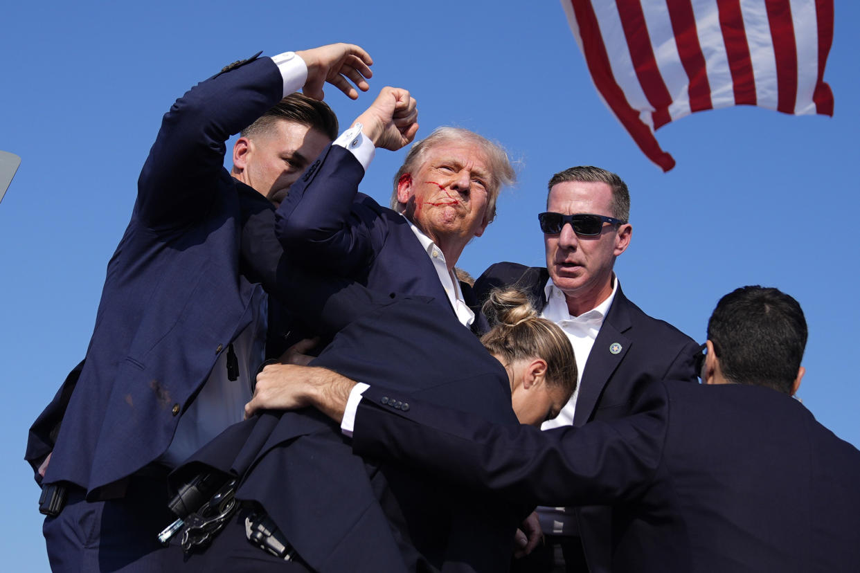 Donald Trump is surrounded by Secret Service agents at a campaign rally.