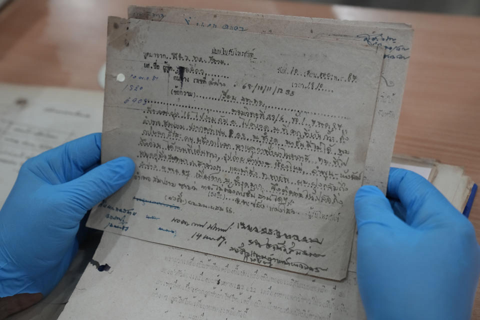 Retired Thai Air Chief Marshal Sakpinit Promthep looks at a WWII-era local Thai police report, in the archive room of the Thai Air Force Museum, In Bangkok, Thailand, Friday April 29, 2022. The document helped locate the possible remains of a U.S. pilot, missing from that time, from a crash site in Lampang province. documenting the crash of a U.S. P-38 plane. (AP Photo/Sakchai Lalit)