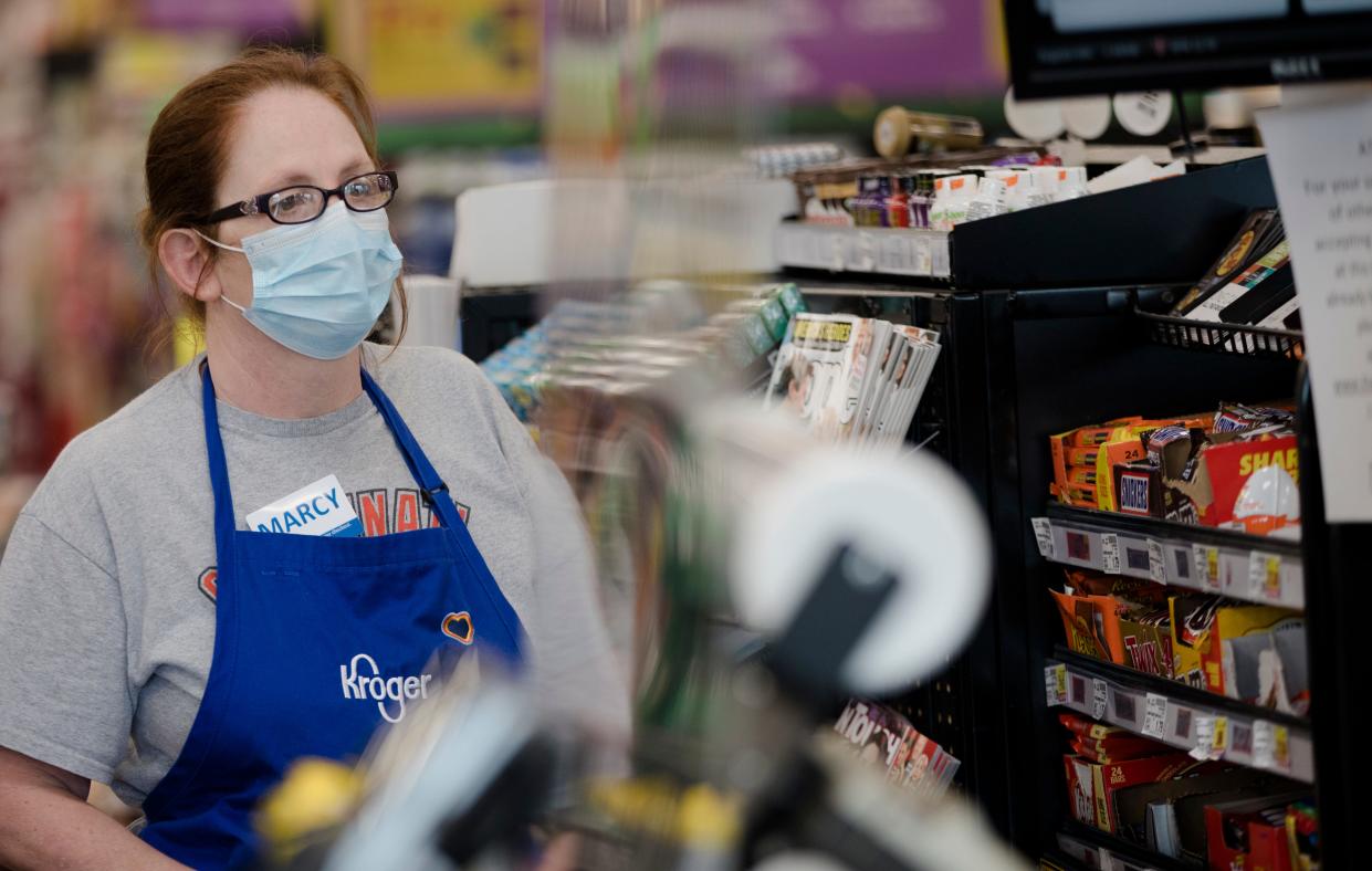 A Kroger employee wears a mask at Kroger on Tuesday, April 7, 2020, in Newport, Ky. Cleaning carts is one of the thing Kroger is doing to limit the spread of the new coronavirus.