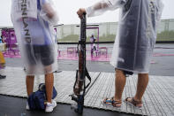 Satu Makela-Nummela, left, of Finland, with her coach, uses a protective rain cover for her shotgun before practice for the women's trap at the Asaka Shooting Range in the 2020 Summer Olympics, Tuesday, July 27, 2021, in Tokyo, Japan. (AP Photo/Alex Brandon)