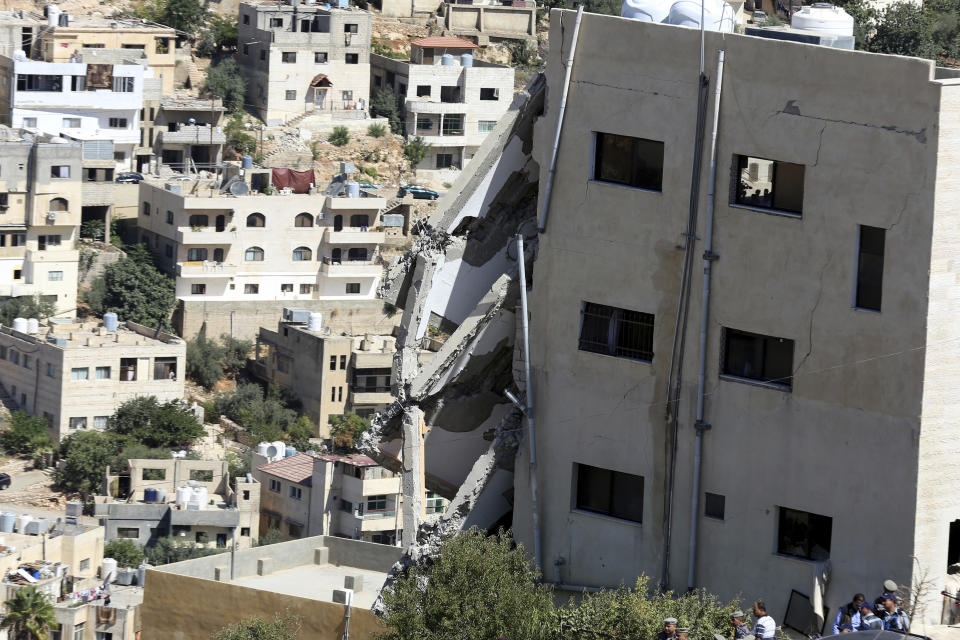 Jordanian security forces inspect the rubble after the side of a building collapsed when assailants opened fire and set off explosions late Saturday that killed four members of the security forces trying to storm the suspected militant hideout in Salt, west of the capital of Amman, Sunday, Aug. 12, 2018. Jordanian search teams have pulled the bodies of three suspected militants from the rubble of their hideout, a government official said Sunday. (AP Photo/Raad Adayleh)