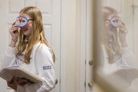 Kate Bulkeley shows her sister, Sutton, a mask she made in school, Friday, Feb. 16, 2024, in Westport, Conn. It is hard to be a teenager today without social media. For those trying to stay off social platforms at a time when most of their peers are immersed, the path can be challenging, isolating and at times liberating. It can also be life-changing. (AP Photo/Julia Nikhinson)