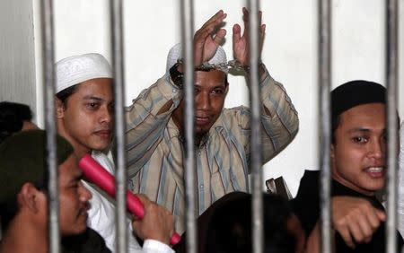 Oman Rochman, also known as Aman Abdurrahman, a radical Muslim cleric, raises his hands in a holding cell as he waits with other militants for their trial in Jakarta August 26, 2010. REUTERS/Dadang Tri/Files