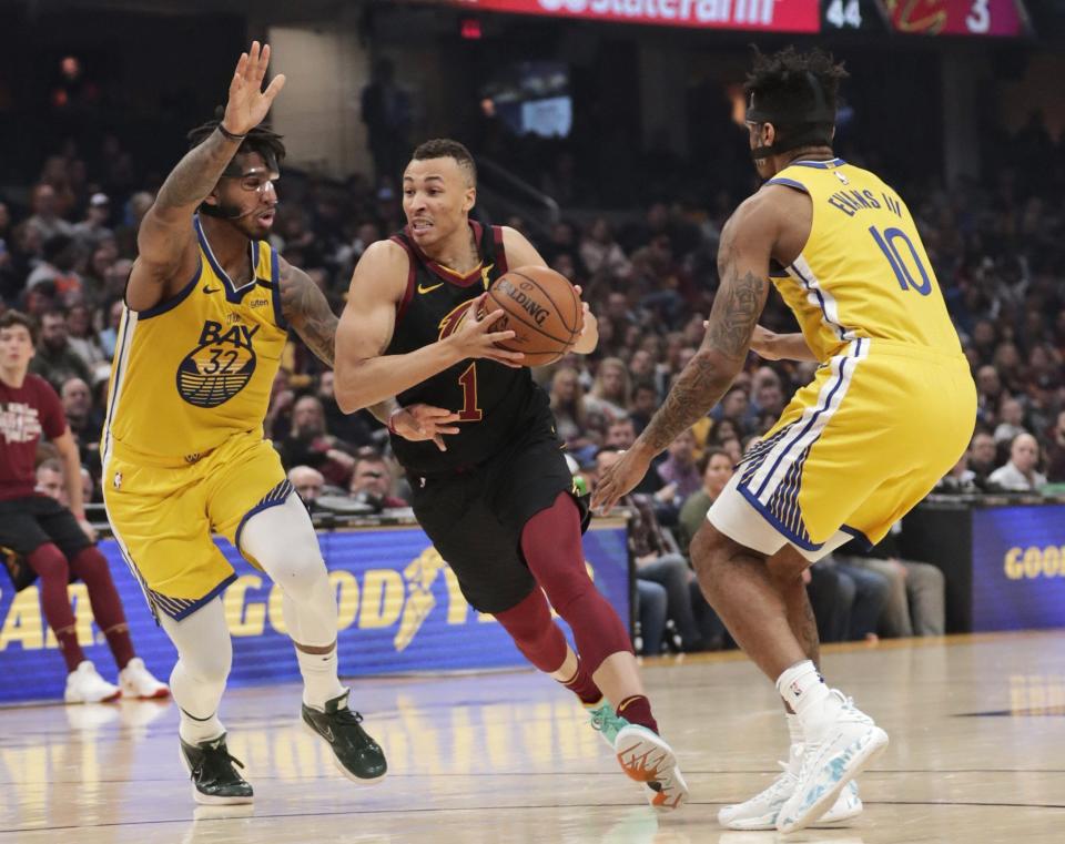 The Cavaliers' Dante Exum drives between Golden State Warriors' Marquese Chriss, left, and Jacob Evans during a 2020 game in Cleveland.