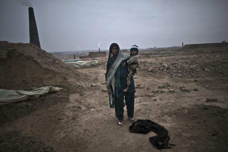 In this Monday, March 3, 2014, photo, Nasreen Ijaz, 24, a Pakistani brick factory worker, poses for a picture with her daughter Attiya, 3, at the site of her work in Mandra, near Rawalpindi, Pakistan. Nasreen and her husband are in debt to their employer the amount of 100,000 rupees (approximately $1000). (AP Photo/Muhammed Muheisen)