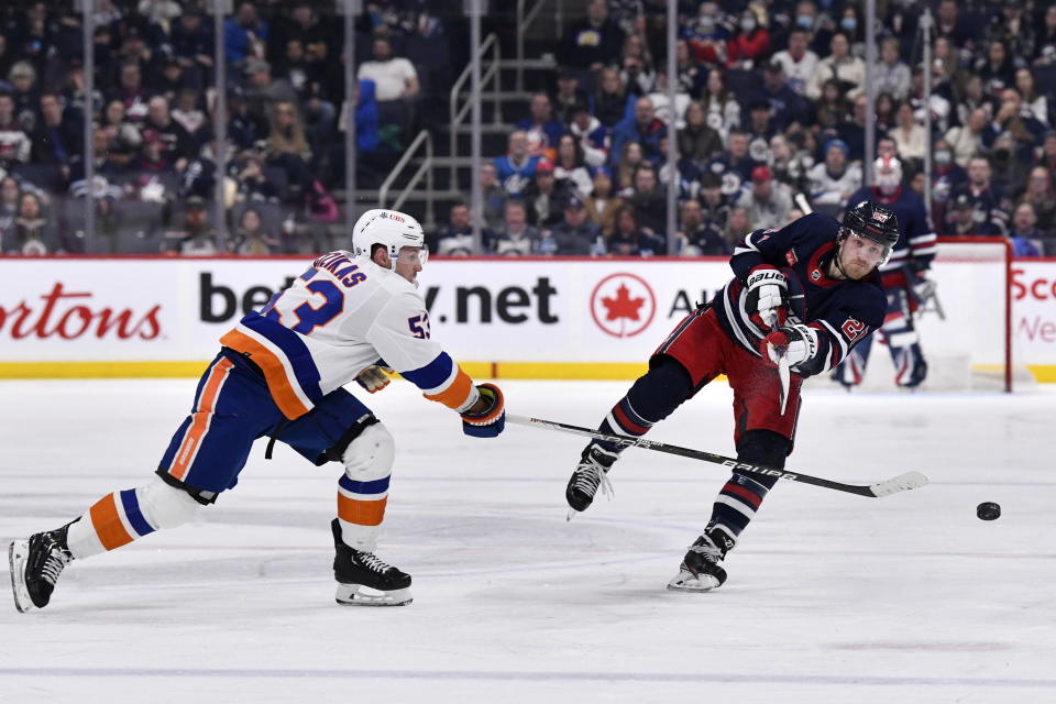 Winnipeg Jets' Nikolaj Ehlers (27) dumps the puck past New York Islanders' Casey Cizikas (53) during second-period NHL hockey game action in Winnipeg, Manitoba, Sunday, Feb. 26, 2023. (Fred Greenslade/The Canadian Press via AP)