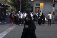 A veiled Iranian woman crosses Jomhouri-e-Eslami (Islamic Republic) St. in downtown Tehran, Iran, Monday, July 30, 2018. Iran's currency plummeted to a record low Monday, a week before the United States restores sanctions lifted under the unraveling nuclear deal, giving rise to fears of prolonged economic suffering and further civil unrest. (AP Photo/Vahid Salemi)