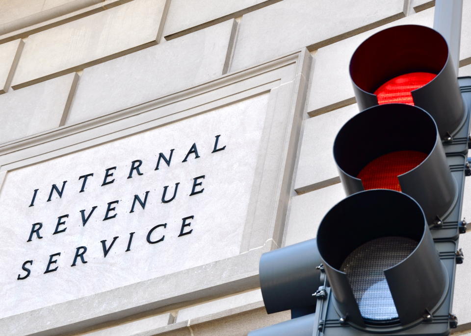 Internal Revenue Service sign with a traffic light in the foreground indicating a red light.