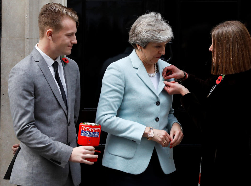 British Legion fundraiser Claire Rowcliffe pins a poppy on to Britain’s Prime Minister Theresa May, as her colleague George Taylor looks on outside 10 Downing Street in London, October 30, 2017. (Picture: REUTERS/Peter Nicholls)