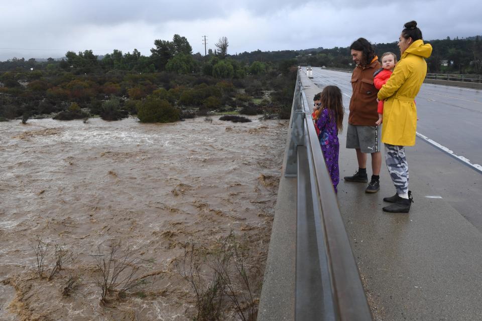 Dalton and Jan De Alba visit the Baldwin Road bridge on Highway 150 with children Alo, 1, Ellie, 7, and Kele, 4, to watch the swelling Ventura River Thursday morning after heavy rain fell overnight.