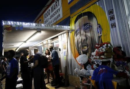 A mural of Alton Sterling is seen as people gather during a vigil at the Triple S Food Mart after the U.S. Justice Department announced they will not charge two police officers in the 2016 fatal shooting of Alton Sterling, in Baton Rouge, Louisiana, U.S., May 2, 2017. REUTERS/Jonathan Bachman