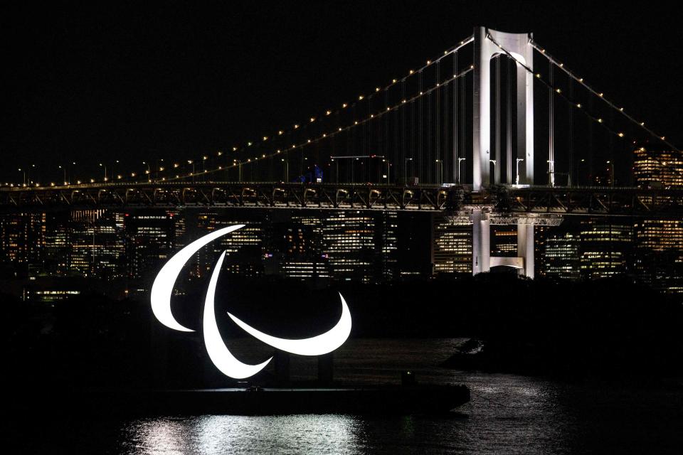 The Paralympics symbol is seen lit up at night with the Rainbow bridge in the background, on the Odaiba waterfront in Tokyo on August 23, 2021.