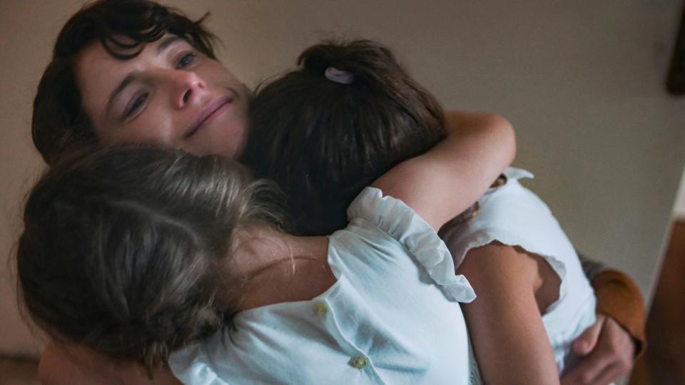 A young Leda (Jessie Buckley) embraces her daughters in "The Lost Daughter."