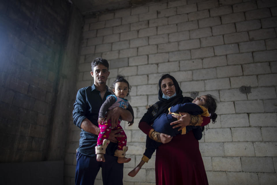 Syrian refugees Raed Mattar, 24, left, poses for a photograph with his wife Ayesha al-Abed, 21, and their daughters Rahaf, 6 years old, right, and Rayan, 18 months old, at an informal refugee camp, in the town of Rihaniyye in the northern city of Tripoli, Lebanon, Tuesday, April 13, 2021. For many Syrian refugee families in Lebanon, Ramadan comes as a hard life of displacement has gotten even harder after a pandemic year that deepened economic woes in their host country. (AP Photo/Hassan Ammar)