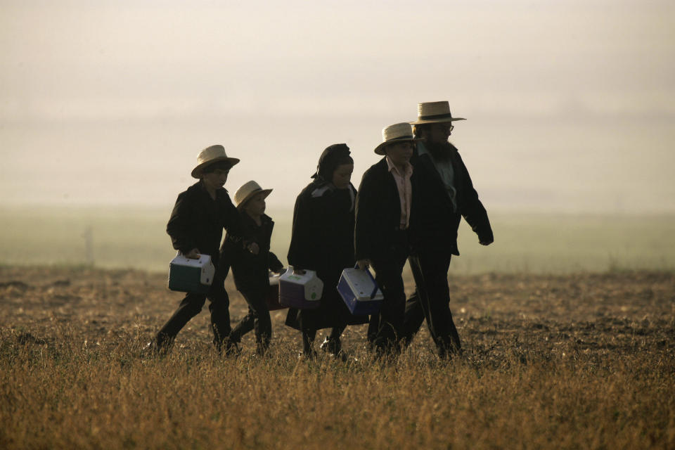 FILE - In this Monday, April 2, 2007, schoolchildren are accompanied by an adult on their way through a fog-shrouded field to the newly-reopened schoolhouse in Nickel Mines, Pa., which was built to replace the razed West Nickel Mines Amish School where a gunman killed five students and himself in October 2006. Conservative Anabaptists largely seek to live separate from mainstream society, emphasize a “non-resistance” to evil and violence, a stance that goes far beyond their refusal to serve in the military, and also have a deep tradition of martyrdom – well-earned, since their forebears suffered fierce persecutions from their 16th century Reformation origins, when they were deemed too radical to Catholics and fellow Protestants alike. (AP Photo/Matt Rourke)