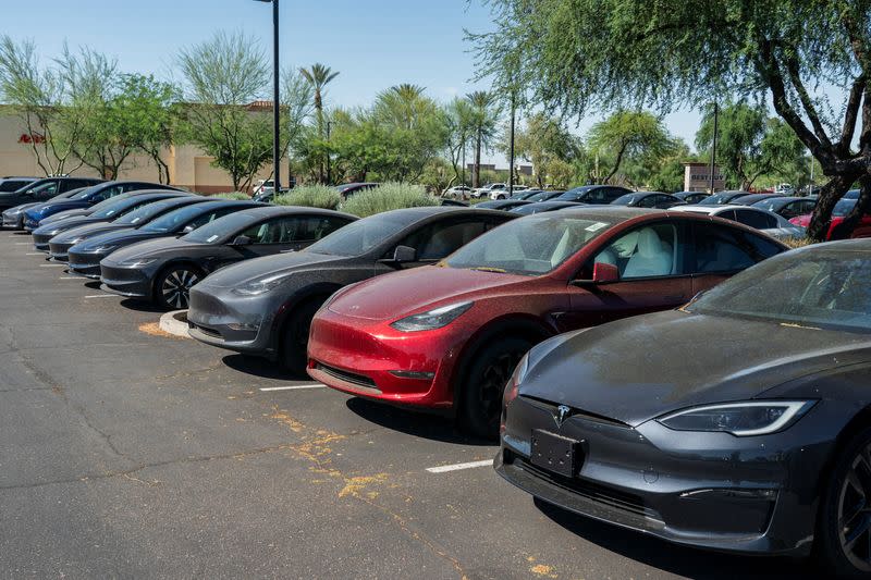 Tesla electric vehicles are parked in a storage lot outside a disused movie theatre in Scottsdale