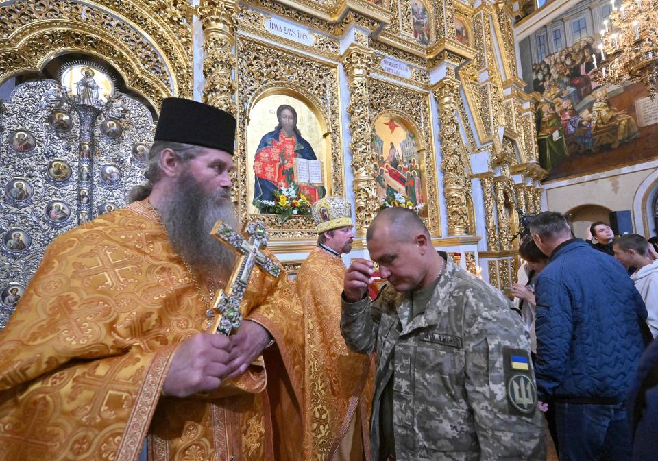 A Ukrainian serviceman (3rdL) makes a cross handsign during a service marking the 1035th anniversary of Kyivan Rus' conversion to Christianity in the Cathedral of the Assumption of the Blessed Virgin (AFP via Getty Images)