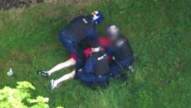 A man in a dressing gown being arrested by three police officers