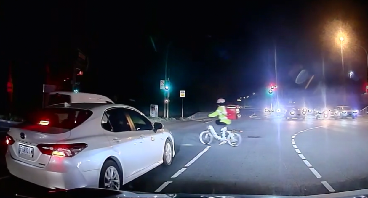 Delivery rider going through intersection after lights turn green.