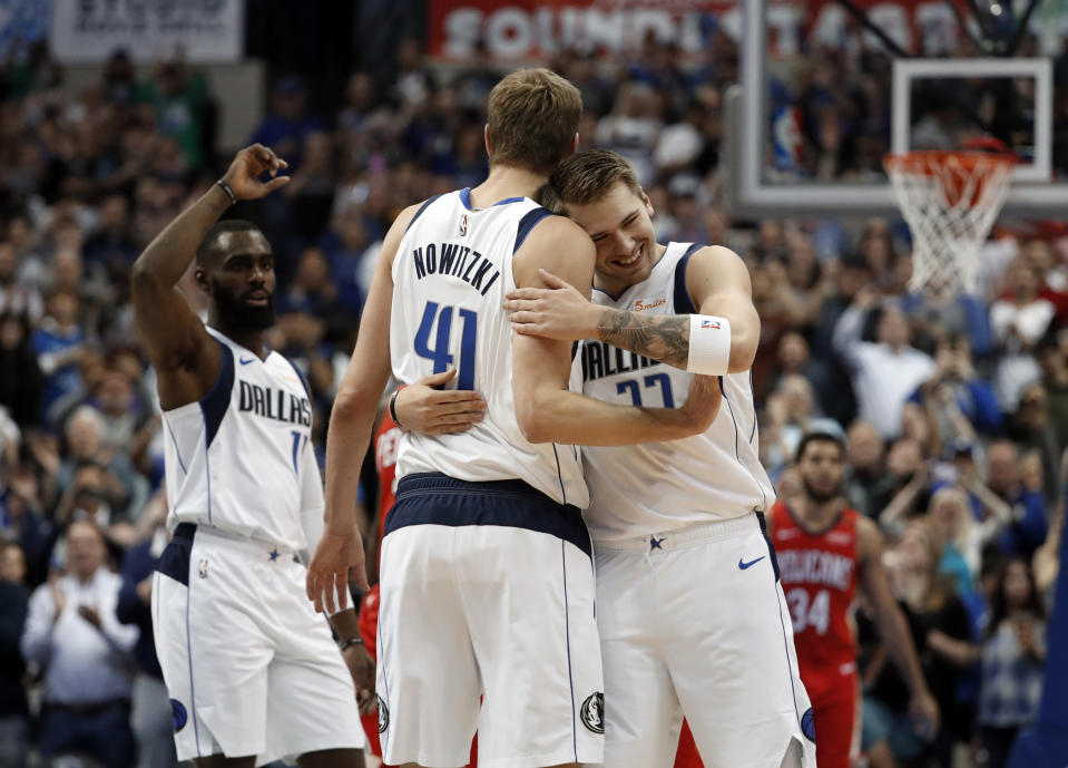 Dallas Mavericks' Tim Hardaway Jr., left, and Luka Doncic (77) celebrate with Dirk Nowitzki (41) after Nowitzki scored a basket in the first half of an NBA basketball game against the New Orleans Pelicans in Dallas, Monday, March 18, 2019. The basket placed Nowitzki as the sixth all-time league leading scorer surpassing Wilt Chamberlain. (AP Photo/Tony Gutierrez)