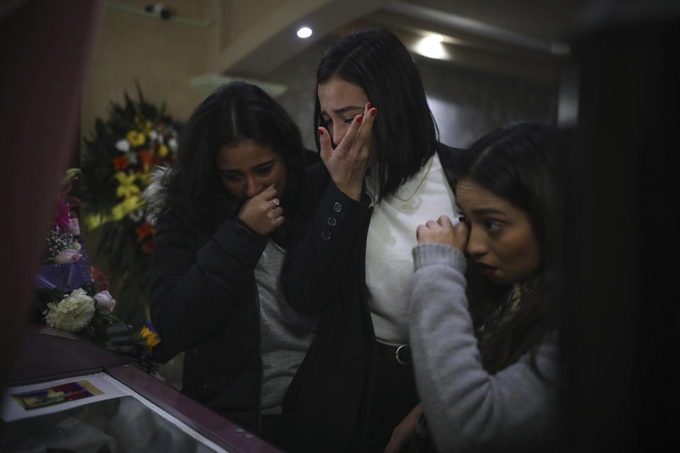 Mourners of slain woman Marbella Valdez grieve over her casket during her wake at a funeral home in Tijuana, Mexico, Friday, Feb. 14, 2020. When the law student’s body was found at a garbage dump in Tijuana, the man who was obsessed with her approached demanded the solve the case, attended her funeral, and a week later was arrested and charged with her murder. The man, identified by Mexican rules only by his first name, Juan, has insisted on his innocence. (AP Photo/Emilio Espejel)