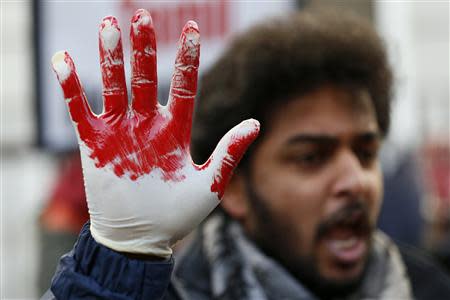 A Tamil demonstrator holds up a hand as they wear a glove covered with fake blood during a protest near the Commonwealth Secretariat in London November 15, 2013. REUTERS/Stefan Wermuth