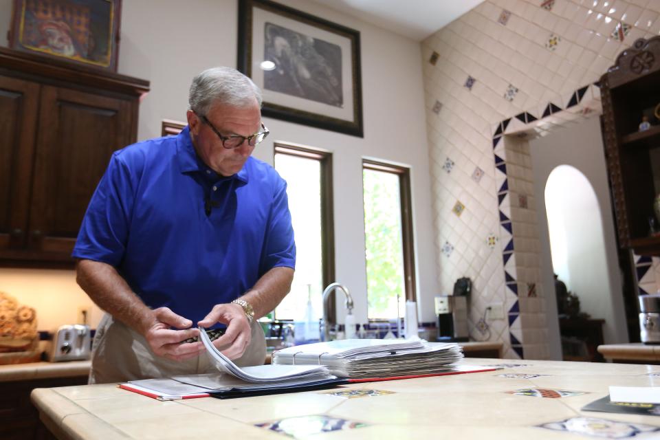 Dee Margo looks through a scrapbook of letters at his home Wednesday, July 28, 2021, that were sent to him from people offering messages of condolences after the Aug. 3, 2019 shooting in El Paso. Margo also kept funeral programs from the funerals he attended.