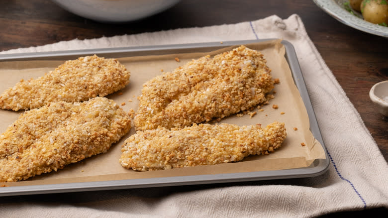 hazelnut crumb-coated chicken cutlets on baking tray