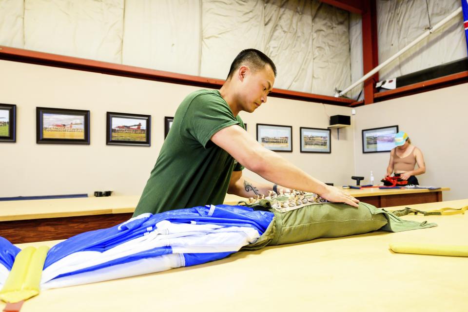 Canadian smokejumper David Pon rigs a parachute on Wednesday, June 5, 2023, in Fort St. John, British Columbia. As nearly 900 fires burn in a Canadian fire season, only one province — British Columbia — relies on smokejumpers to help fight the blazes. Its history dates back to 1998. (AP Photo/Noah Berger)