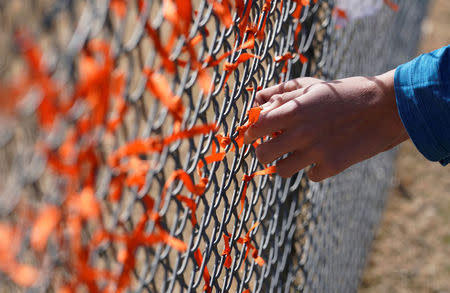 Columbine High School student Andrew Pavicich ties a memorial ribbon on the fence outside the school during a National School Walkout to honor the 17 students and staff members killed at Marjory Stoneman Douglas High School in Parkland, Florida, in Littleton, Colorado, U.S. March 14, 2018. REUTERS/Rick Wilking