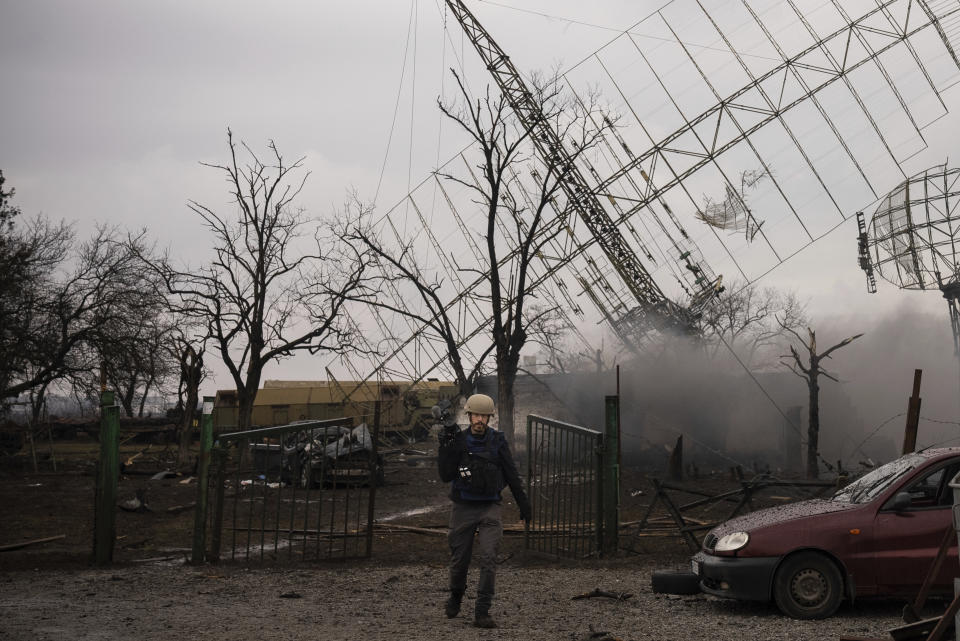 FILE - Associated Press videographer Mstyslav Chernov walks amid smoke rising from an air defense base in the aftermath of a Russian strike in Mariupol, Ukraine, on Feb. 24, 2022. Chernov and Evgeniy Maloletka, two Ukrainians who documented the horrors of the Russian invasion and siege of Mariupol for The Associated Press, are being honored for their courage with Colby College's Lovejoy Award. (AP Photo/Evgeniy Maloletka, File)