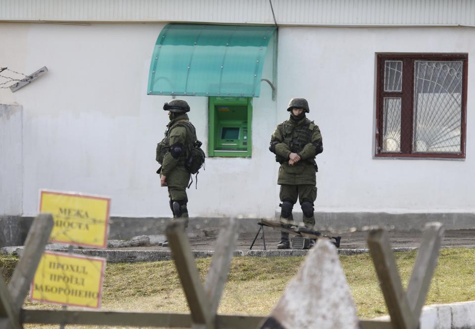 Armed men believed to be Russian military personnel stand near the territory of a Ukrainian military unit in the village of Perevalnoye outside Simferopol