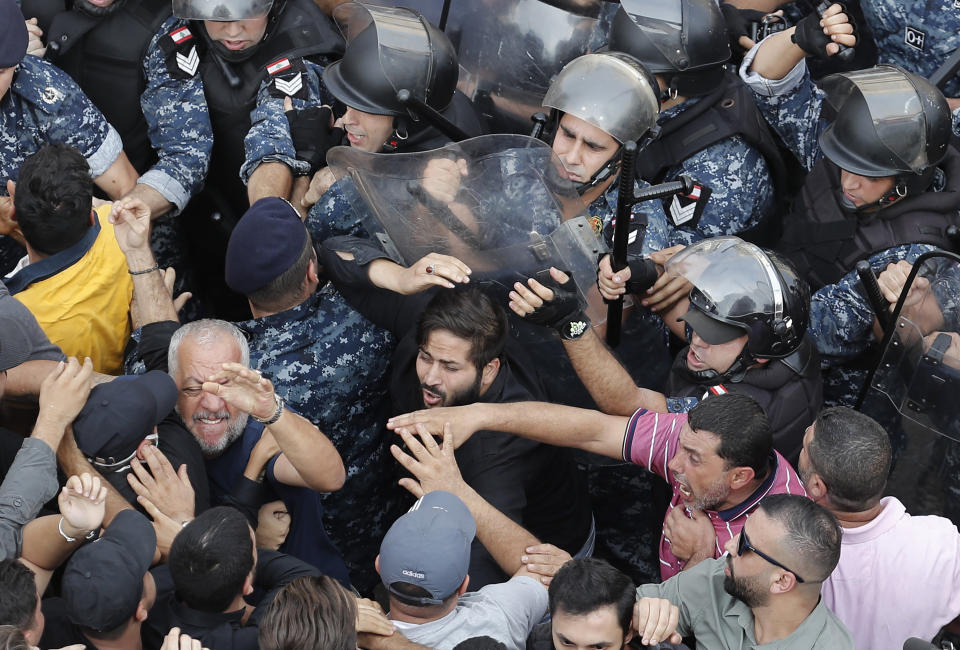 Lebanese riot policemen clashing with Hezbollah supporters during a protest near the government palace, in downtown Beirut, Lebanon, Friday, Oct. 25, 2019. Hundreds of Lebanese protesters set up tents, blocking traffic in main thoroughfares and sleeping in public squares on Friday to enforce a civil disobedience campaign and keep up the pressure on the government to step down. (AP Photo/Hussein Malla)