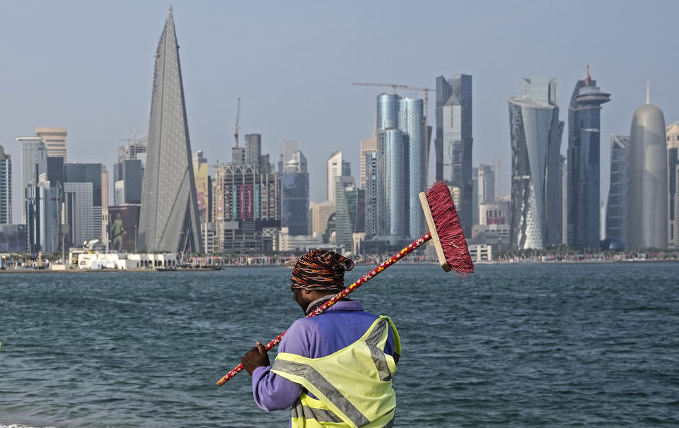 A worker walks at the Doha Corniche in front of the skyline on the day before the start of the Soccer World Cup in Doha, Qatar, Saturday, Nov. 19, 2022. (AP Photo/Martin Meissner)