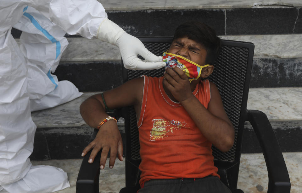 A child grimaces as a health worker takes a nasal swab sample for COVID- 19 testing through rapid antigen methodology, in New Delhi, India , Friday, Aug. 7, 2020. As India hit another grim milestone in the coronavirus pandemic on Friday, crossing 2 million cases and more than 41,000 deaths, community health volunteers went on strike complaining they were ill-equipped to respond to the wave of infection in rural areas. (AP Photo/Manish Swarup)