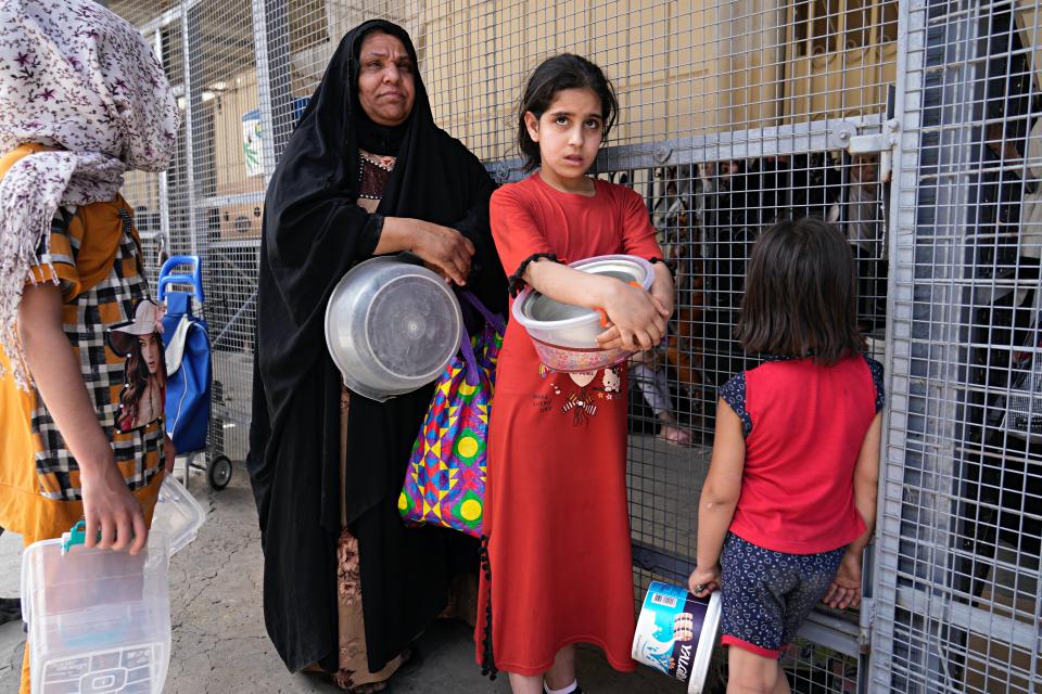 People receive free food being distributed ahead of Iftar, the evening meal breaking the Ramadan fast, at the Abdul-Qadir al-Gailani mosque in Baghdad, Iraq, Saturday, April 2, 2022. Muslims throughout the world are marking the Ramadan -- a month of fasting during which observants abstain from food, drink and other pleasures from sunrise to sunset. (AP Photo/Hadi Mizban)