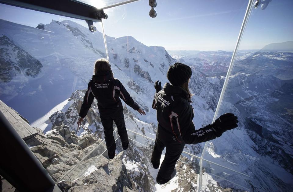 Employees, wearing slippers to protect the glass floor, stand in the 'Step into the Void' installation during a press visit at the Aiguille du Midi mountain peak above Chamonix, in the French Alps, December 17, 2013. REUTERS/Robert Pratta