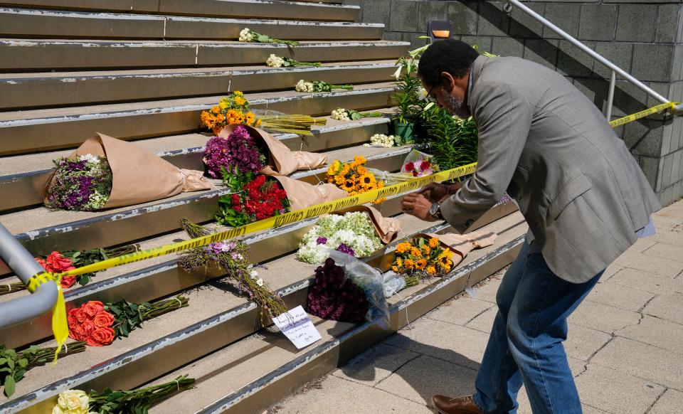 Andrew Thuita takes photos of a memorial outside of Old National Bank  Tuesday, April 11, 2023 after a mass shooting Monday morning that left six dead, including the shooter, and another 8 injured. Thuita, a retired school teacher said, "I am so feed up with shootings in general". Thuita said he missed being involved at the shooting at Kroger in 2018, minutes. He just left the store shortly before the shooting took place.