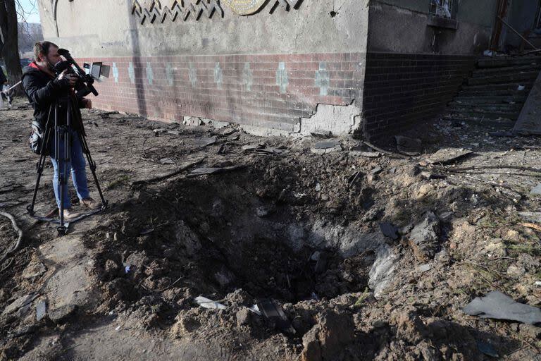 Un camarógrafo filma un cráter junto a un edificio universitario dañado como resultado de un ataque con drones en Odesa el 8 de febrero de 2024, en medio de la invasión rusa de Ucrania.