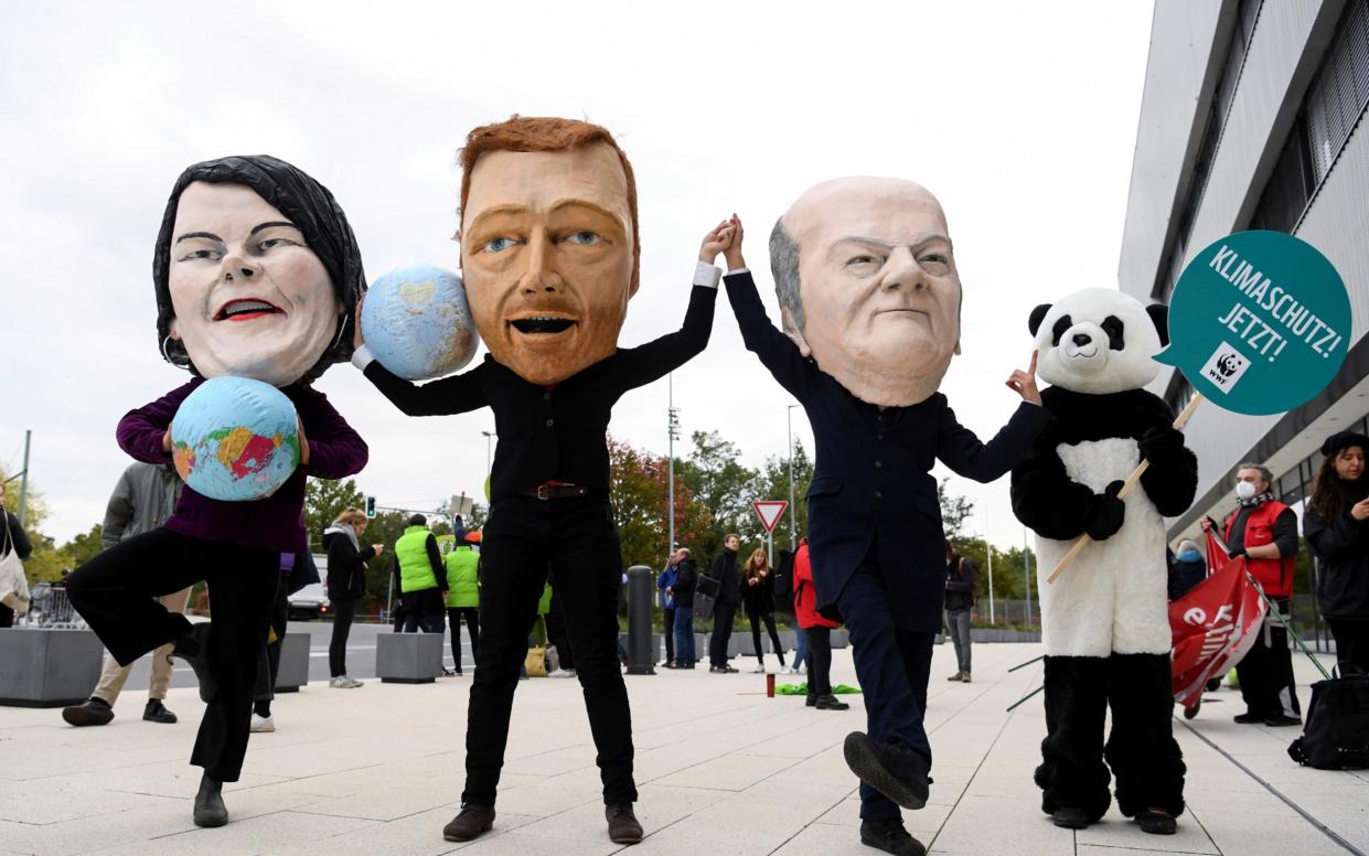 Protesters wearing masks depicting Germany's Greens party co-leader Annalena Baerbock, Free Democratic Party (FDP) leader Christian Lindner and Social Democratic Party (SPD) top candidate for chancellor Olaf Scholz as politics arrive at a meeting for exploratory talks for a possible new government coalition in Berlin, Germany, October 15, 2021. REUTERS/Annegret Hilse TPX IMAGES OF THE DAY - ANNEGRET HILSE /REUTERS