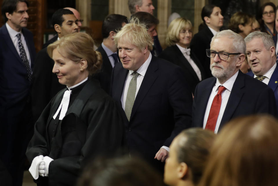 Britain's Prime Minister Boris Johnson, centre left, and opposition Labour Party Leader Jeremy Corbyn, right, walk through the Commons Members Lobby, during the state opening of Parliament, in London, Thursday, Dec. 19, 2019. Queen Elizabeth II formally opened a new session of Britain's Parliament on Thursday, with a speech giving the first concrete details of what Prime Minister Boris Johnson plans to do with his commanding House of Commons majority. (AP Photo/Kirsty Wigglesworth, Pool)
