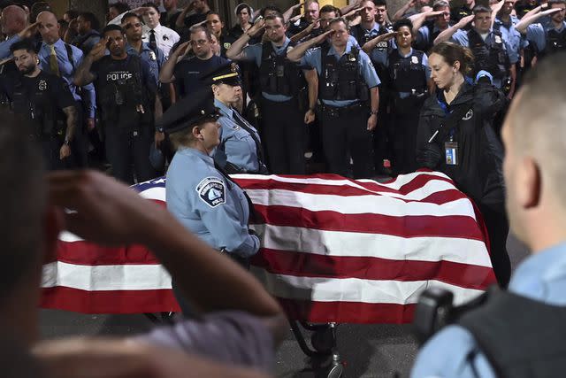 <p>Aaron Lavinsky/Star Tribune via AP</p> Law enforcement officers salute Minneapolis police Officer Jamal Mitchell as he is escorted to a waiting medical examiner's vehicle in Minneapolis