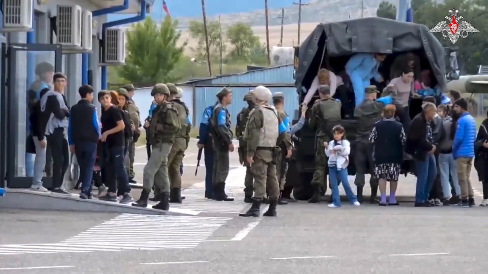 In this photo taken from video released by Russian Defense Ministry Press Service on Thursday, Sept. 21, 2023, Russian peacekeepers help ethnic Armenians to leave a truck at a camp near Stepanakert in Nagorno-Karabakh. Thousands of Nagorno-Karabakh residents flocked to a camp operated by Russian peacekeepers to avoid the fighting, while many others gathered at the airport of the regional capital, Stepanakert, hoping to flee the region. (Russian Defense Ministry Press Service via AP)