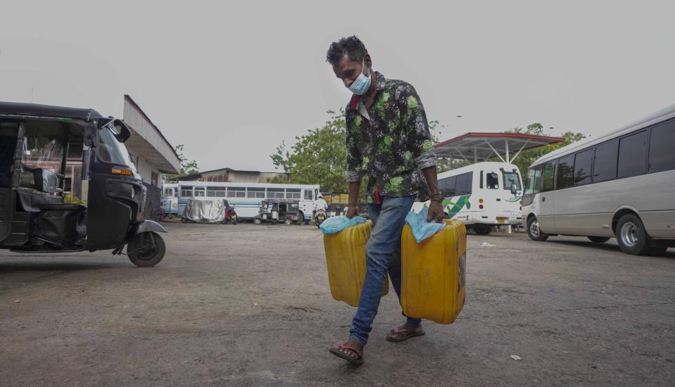A Sri Lankan man walks after buying fuel for power generators in Colombo, Sri Lanka, Wednesday, March 2, 2022. Authorities in Sri Lanka are imposing rolling power cuts across the island nation as its deepening financial crisis leads to shortages of fuel and handicaps its power grid. A currency crunch has hindered imports of fuel and other essentials from overseas, including milk powder, cooking gas, and petrol. (AP Photo/Eranga Jayawardena)