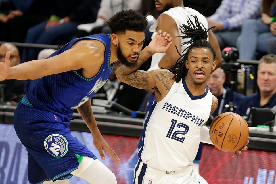 Memphis Grizzlies guard Ja Morant (12) drives on Minnesota Timberwolves center Karl-Anthony Towns (32) during the first half of Game 3 of an NBA basketball first-round playoff series Thursday, April 21, 2022, in Minneapolis. (AP Photo/Andy Clayton-King)