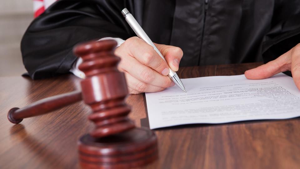 Close-up Of Male Judge  Writing On Paper In Courtroom.