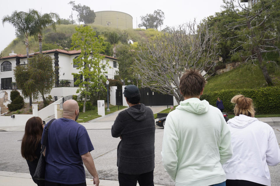 Residents and neighbors look towards National Transportation Safety Board investigators inspecting a downed plane on a steep hill above homes at Beverly Glen Circle in Los Angeles Sunday, April 30, 2023. Fire department officials said a person was found dead following an intensive search for the single-engine airplane that crashed in a foggy area Saturday night. (AP Photo/Damian Dovarganes)