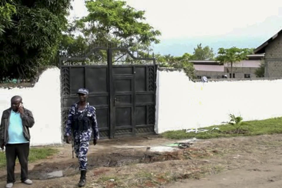In this image made from video, security forces are seen outside the gate of the Lhubiriha Secondary School following an attack on the school near the border with Congo, in Mpondwe, Uganda, Saturday, June 17, 2023. Ugandan authorities recovered the bodies of dozens of people including students who were burned, shot or hacked to death after suspected rebels attacked the school, the local mayor said Saturday. (AP Photo)